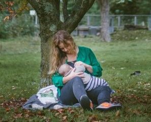 mother breastfeeding newborn under a tree