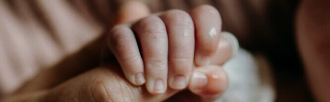 newborn holding mother's finger